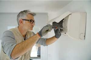 Man making repairs to mini split indoor unit. All Seasons Heating & Cooling in Vancouver WA provides expert air conditioning repair.