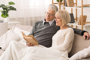 Man and woman sitting comfortably at home under blanket. ll Seasons Heating & Cooling provides exceptional gas furnace repair in Vancouver WA and Portland OR.