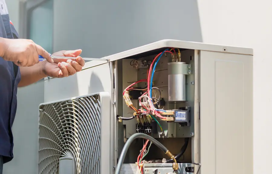 A technician using a screwdriver to repair an air conditioner
