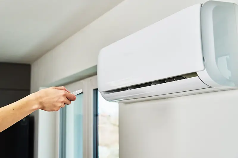 A Portland homeowner pointing a remote control at their nonfunctional AC unit.